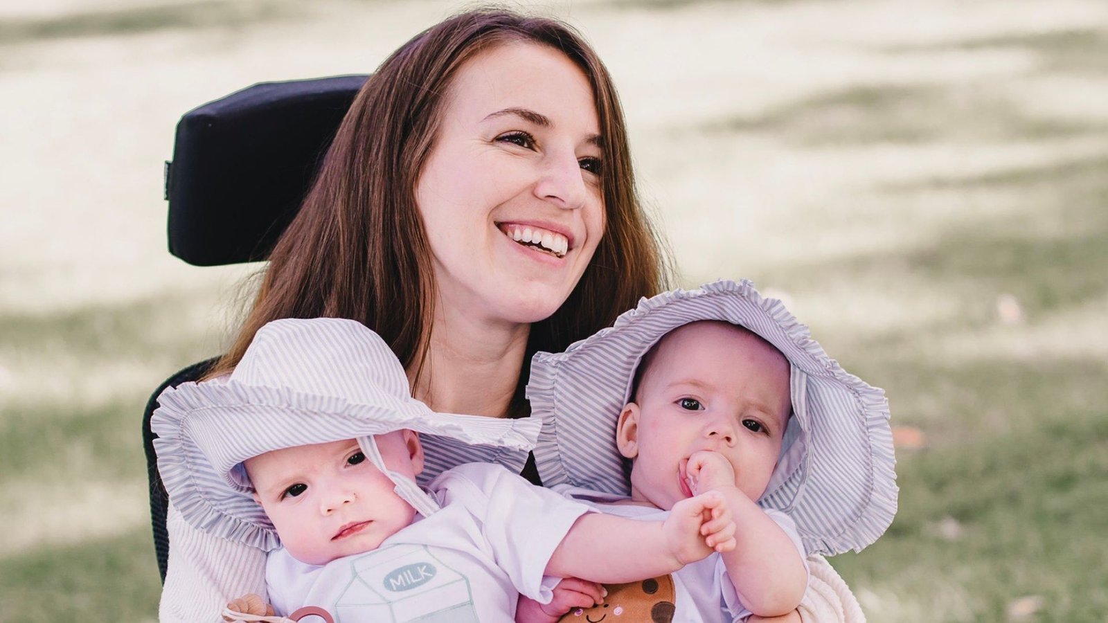 Dani Izzie smiling in her wheelchair with her twin girls.