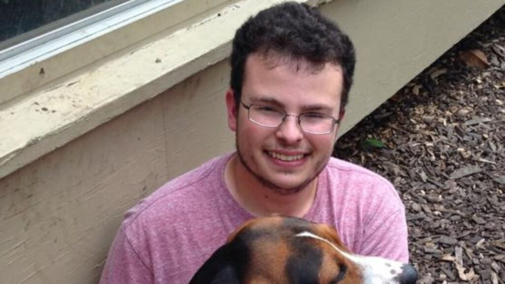 Jason P. Harris smiling while holding his dog.