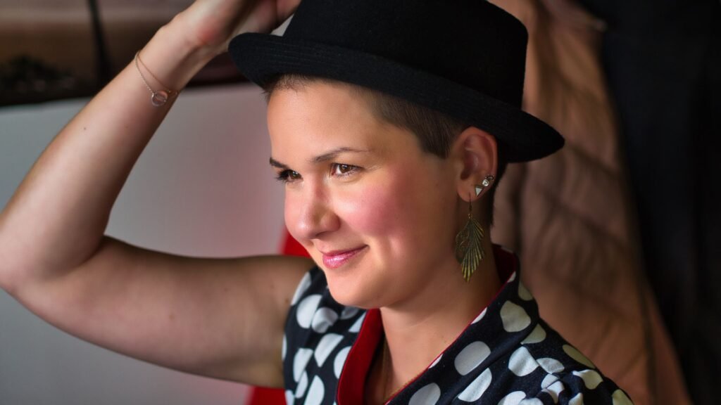 Karina Sturm smiling, wearing a black hat and a polka dot shirt.
